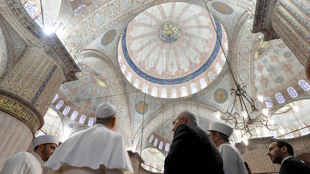 Papst Leo steht mit dem Rücken zur Kamera. Er schaut sich die Kuppel von der Blauen Moschee in Istanbul an.