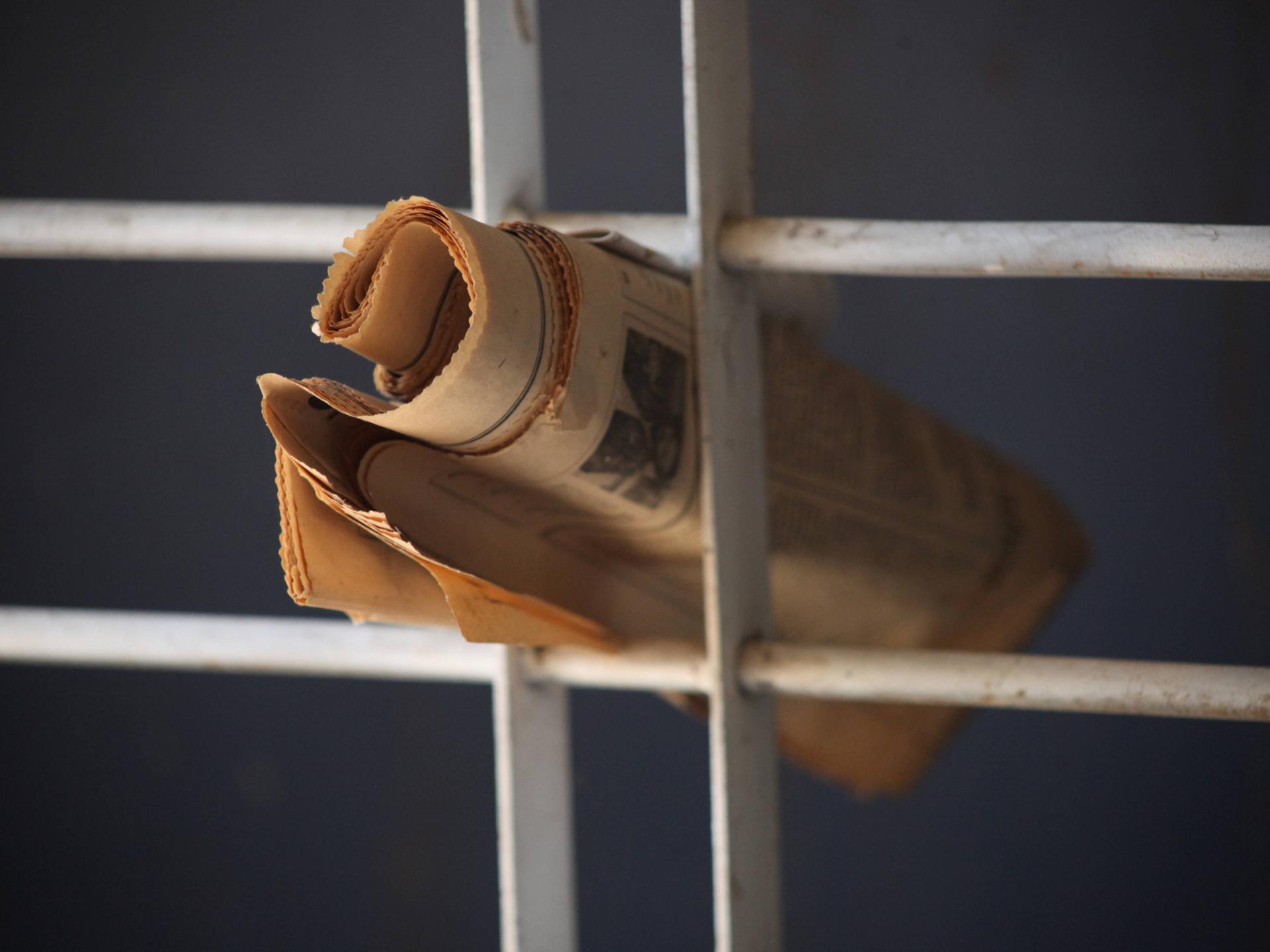 Eine Zeitung steckt in einem Gitter.