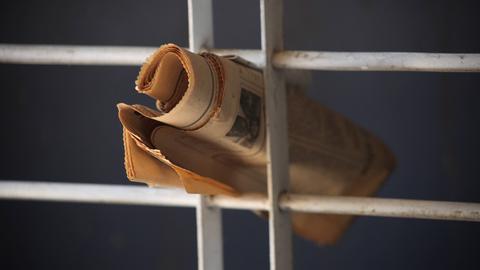 Eine Zeitung steckt in einem Gitter.