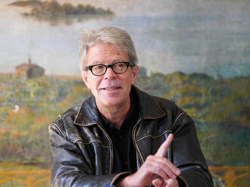 US-Schriftsteller Jonathan Franzen spricht während einer Pressekonferenz in Lübeck. Er blickt zur Seite und hat einen Zeigefinger erhoben.