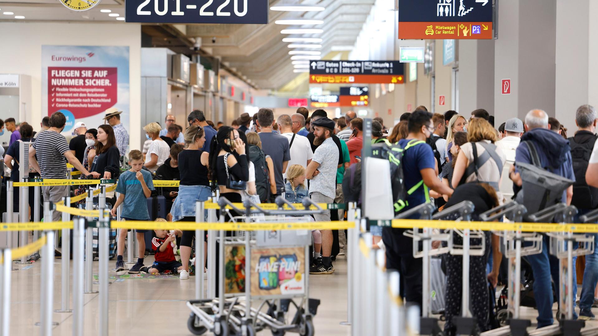 Menschen stehen in einer langen Schlange an. Sie warten auf die Sicherheits-Kontrolle am Flughafen Köln/Bonn.