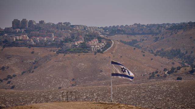 Eine israelische Flagge auf einem Hügel. Im Hintergrund ist eine Siedlung zu sehen. Eine israelische Flagge auf einem Hügel. Im Hintergrund ist eine Siedlung zu sehen.