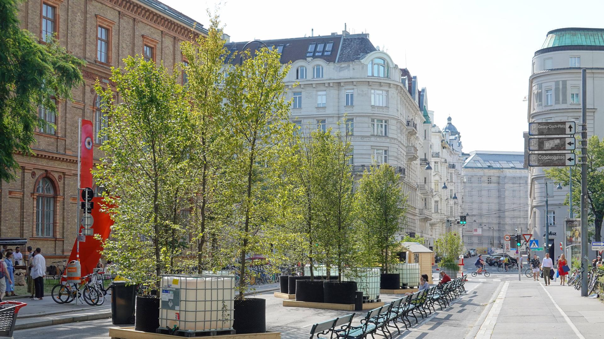 Das Bild zeigt den Oskar-Kokoschka-Platz in Wien: eine Reihe von Bänken steht vor begrünten Flächen. Es gehen ein paar Passanten durchs Bild, im Hintergrund sind Gründerzeit-Häuser zu sehen, einige gastronomische Angebote und Boutiquen sind auch vorhanden. Der Platz ist autofrei. Das Bild zeigt den Oskar-Kokoschka-Platz in Wien: eine Reihe von Bänken steht vor begrünten Flächen. Es gehen ein paar Passanten durchs Bild, im Hintergrund sind Gründerzeit-Häuser zu sehen, einige gastronomische Angebote und Boutiquen sind auch vorhanden. Der Platz ist autofrei.