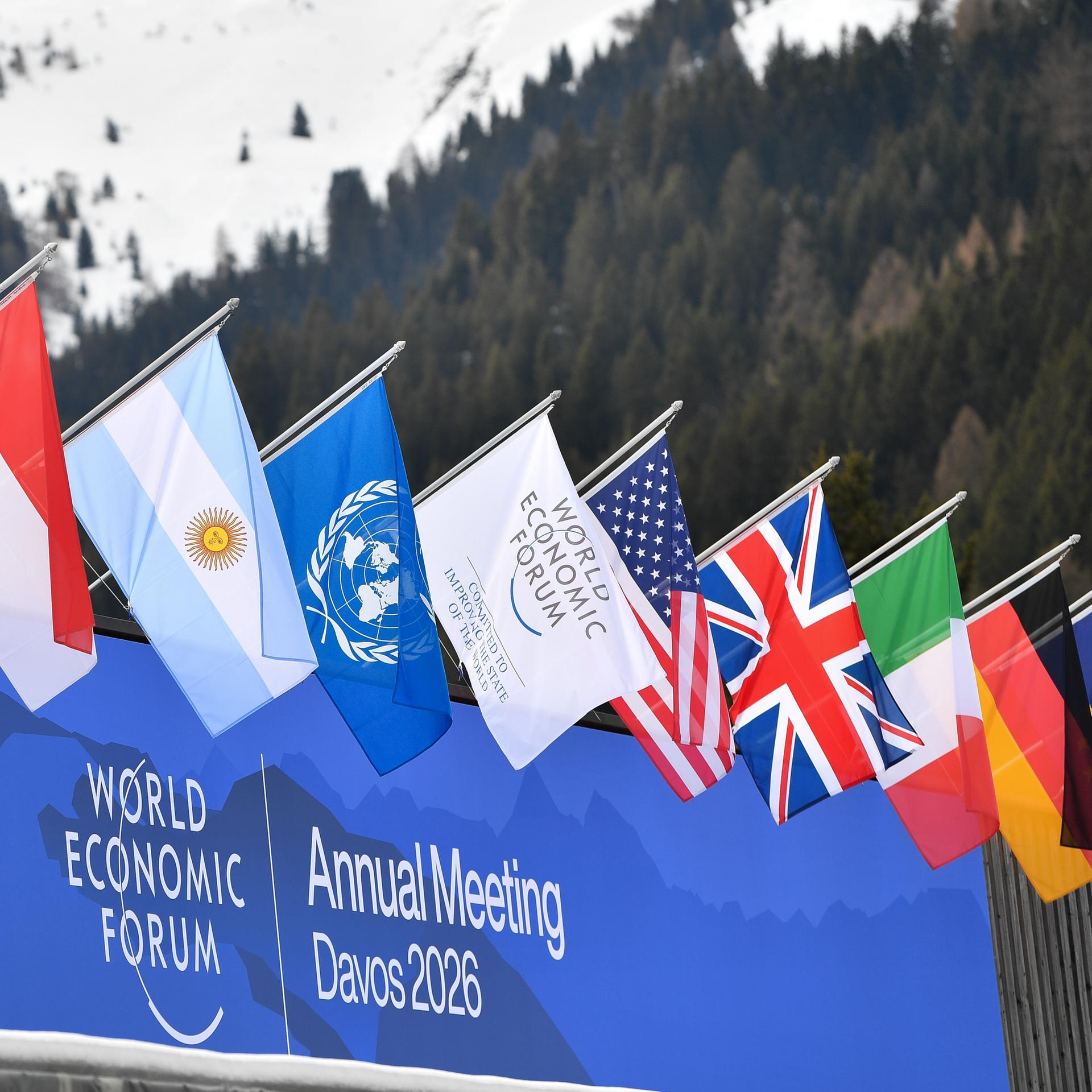 Flaggen wehen vor dem Schriftzug "World Economic Forum - Annual Meeting Davos 2026".