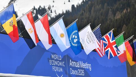 Flaggen wehen vor dem Schriftzug "World Economic Forum - Annual Meeting Davos 2026".