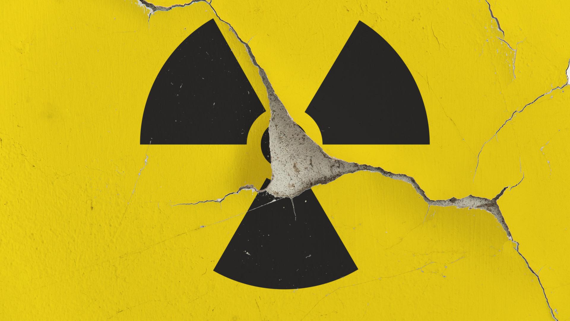 Auf einer Gebäudewand mit aufgeplatzter Fassade ist das Symbol für Radioaktivität zu sehen. 