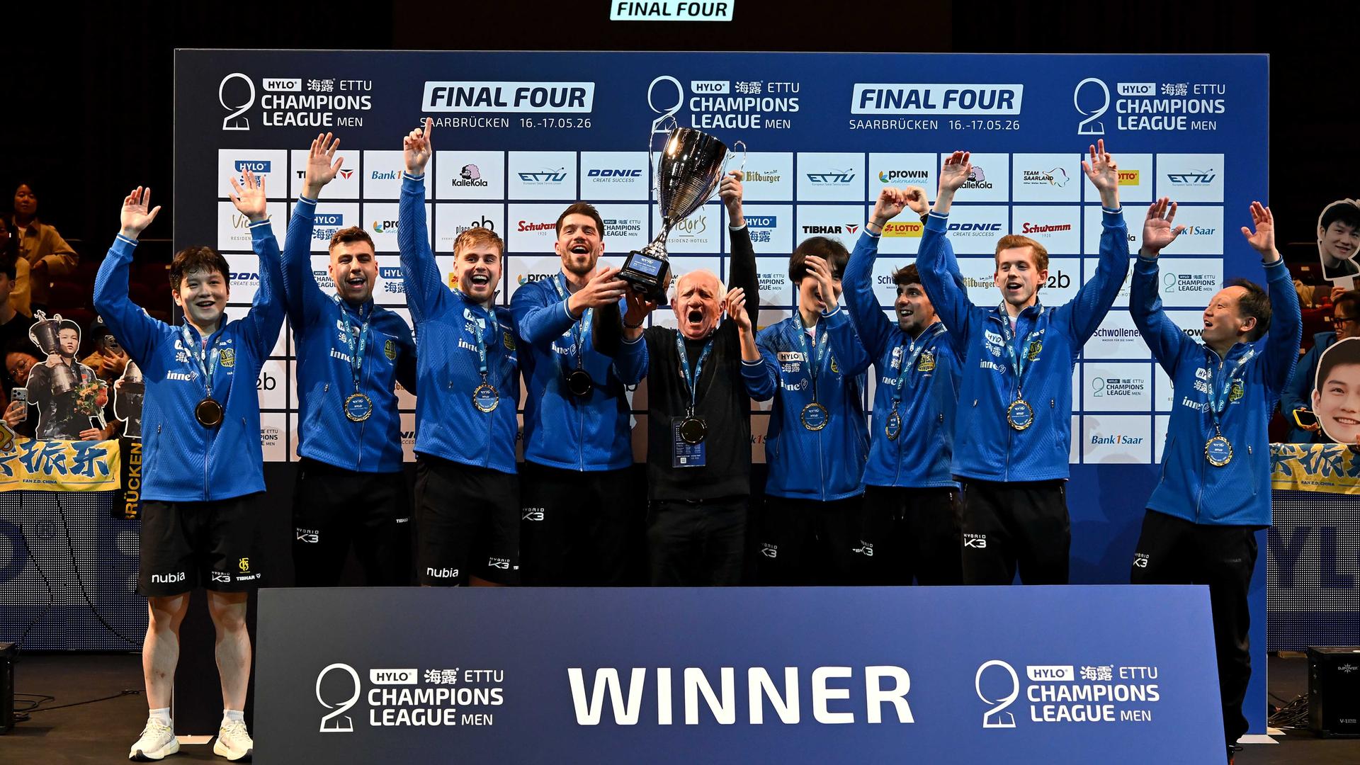 Die Tischtennis-Mannschaft von Saarbrücken feiert mit dem Champions-League-Pokal.