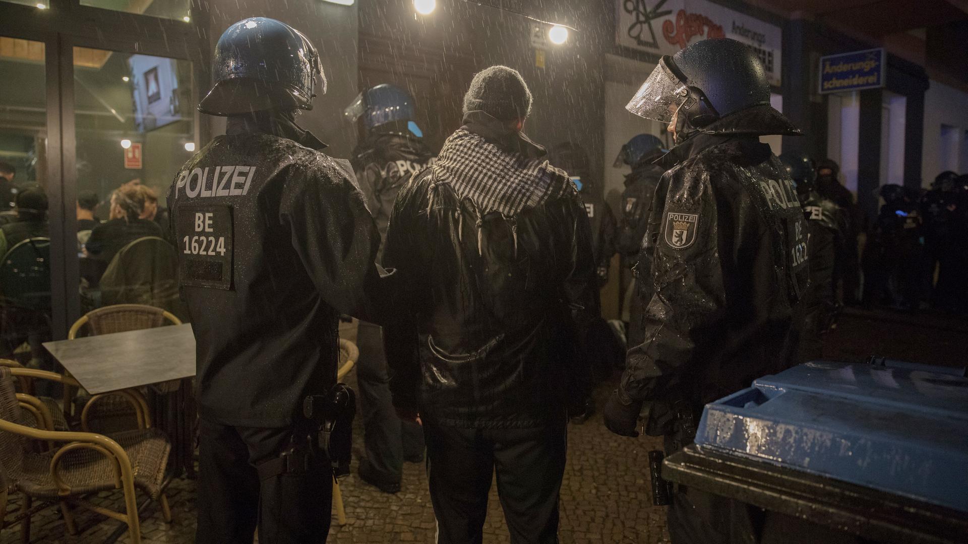 Ein Mann mit Palästinensertuch zwischen zwei deutschen Polizisten im Berliner Stadtteil Neukölln. 7. Oktober 2023.