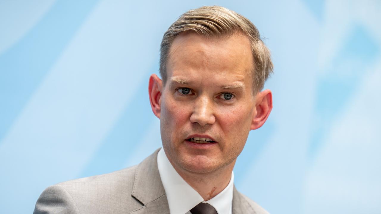 Das Bild zeigt den Oberkörper Streecks vor einer hellblau-weißen Wand. Er trägt ein graues Jackett mit Krawatte und sagt gerade etwas mit konzentriertem Blick. 