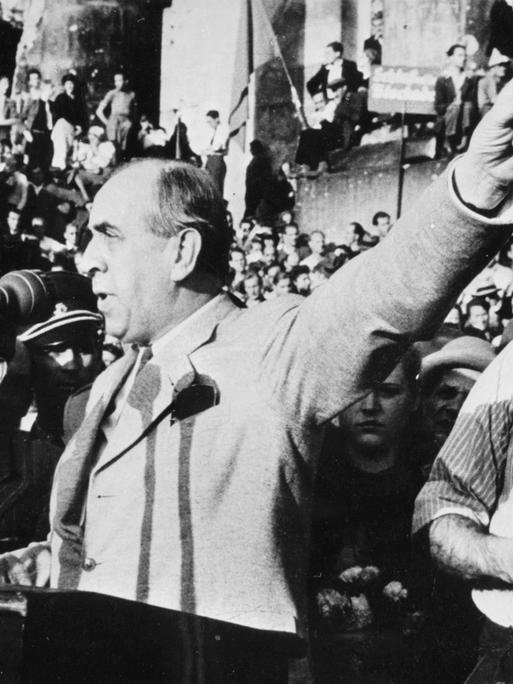 Schwarweiß-Foto zeigt Ernst Reuter gestikulierend vor einem Mikrofonneben ihm steht der SPD-Vorsitzende Franz Neumann