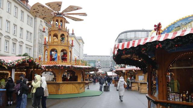 Menschen stehen auf einem Weihnachts-Markt neben den Buden.