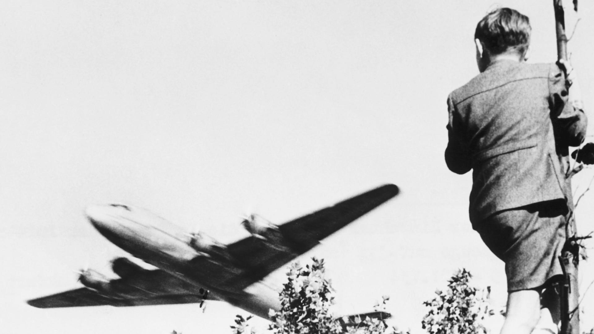 Ein Junge verfolgt von einem Baum aus den Landeanflug eines US-amerikanischen Transportflugzeugs auf den Berliner Flughafen Tempelhof. Ein Junge verfolgt von einem Baum aus den Landeanflug eines US-amerikanischen Transportflugzeugs auf den Berliner Flughafen Tempelhof.