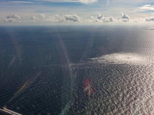 Blick aus einem Hubschrauber auf eine Wasserfläche mit einem großen Kreis von Wasserblasen.