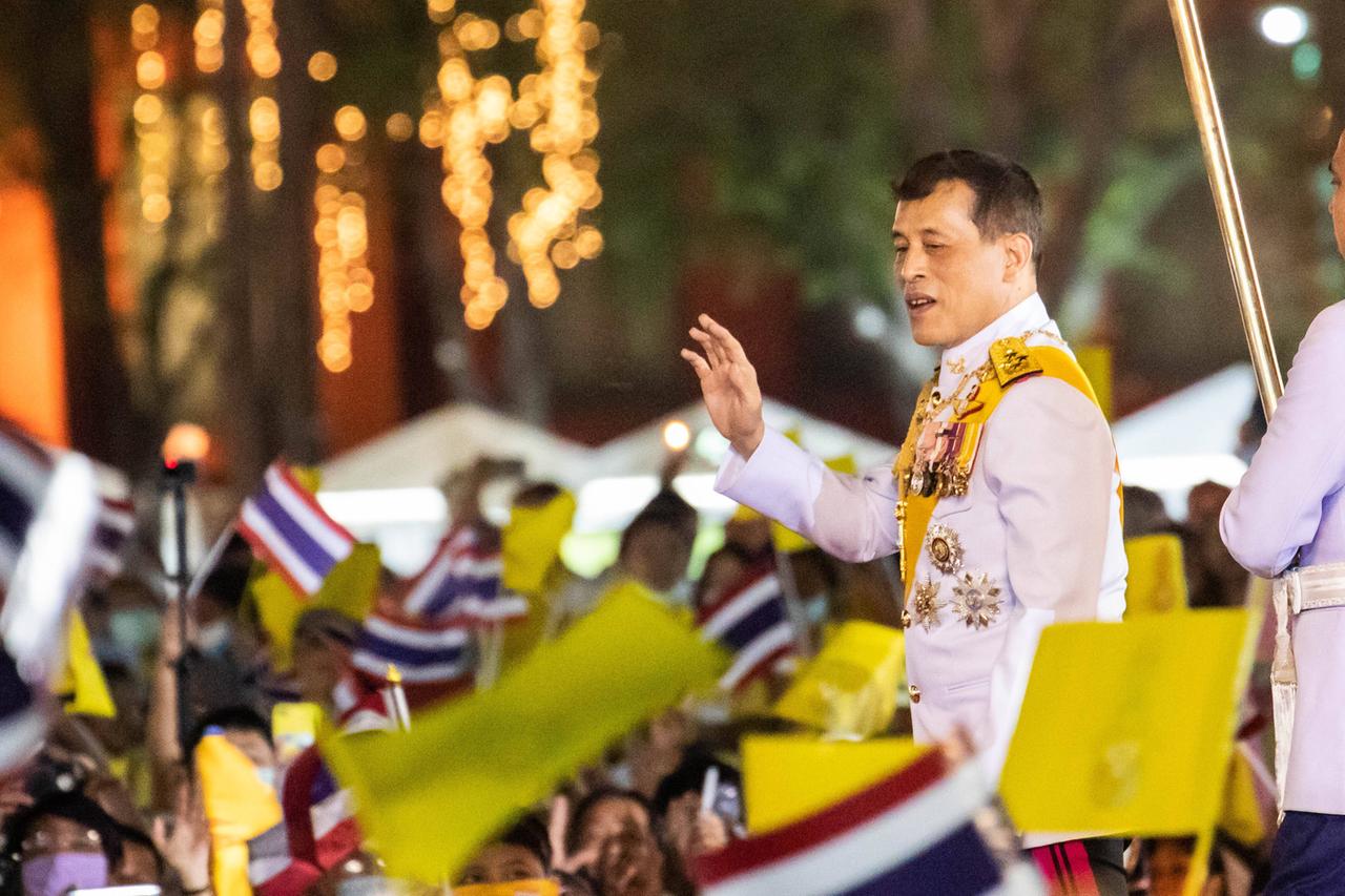 König Maha Vajiralongkorn 2020 in Bangkok: Ein Mann in einer weißer Uniform wird von zahlreichen Menschen mit Fähnchen bejubelt.