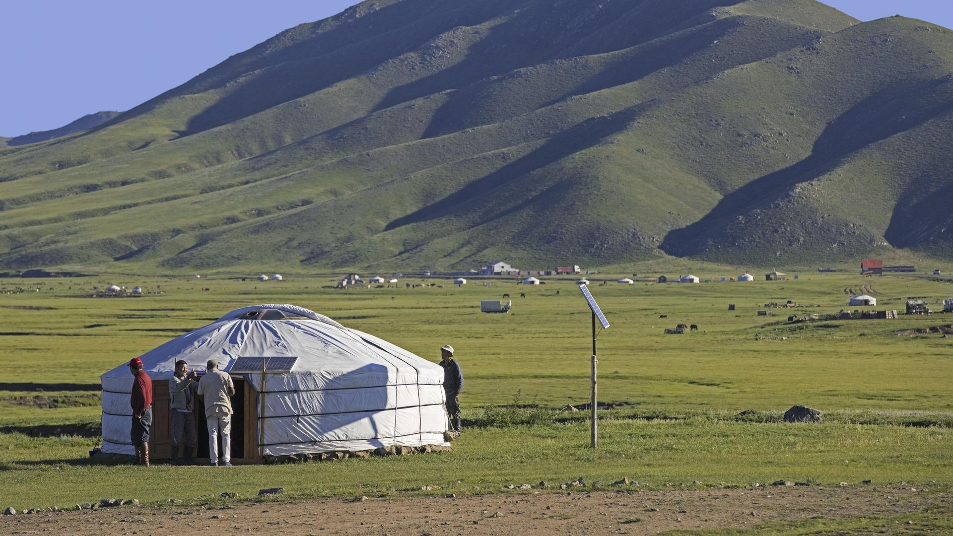 Mongolische Männer vor einem traditionellen Ger, einer mit Solarzellen ausgestatteten Jurte in der Steppe der Mongolei im Sommer.