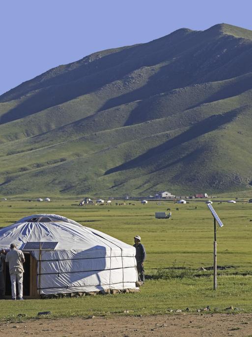 Mongolische Männer vor einem traditionellen Ger, einer mit Solarzellen ausgestatteten Jurte in der Steppe der Mongolei im Sommer.