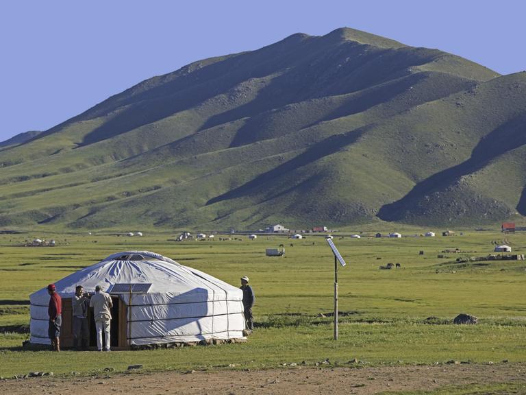 Mongolische Männer vor einem traditionellen Ger, einer mit Solarzellen ausgestatteten Jurte in der Steppe der Mongolei im Sommer.