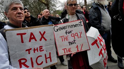 Londoner Demonstrierende halten Schilder mit der Aufschrift "Tax the rich" und"Government for the 99% not the 1%". social and economic justice. Kein Aufnahmedatum.