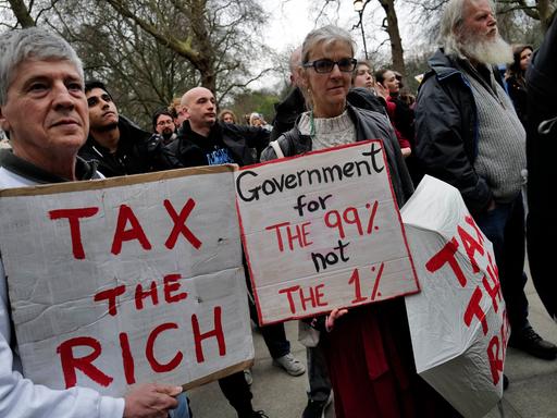 Londoner Demonstrierende halten Schilder mit der Aufschrift "Tax the rich" und"Government for the 99% not the 1%". social and economic justice. Kein Aufnahmedatum.