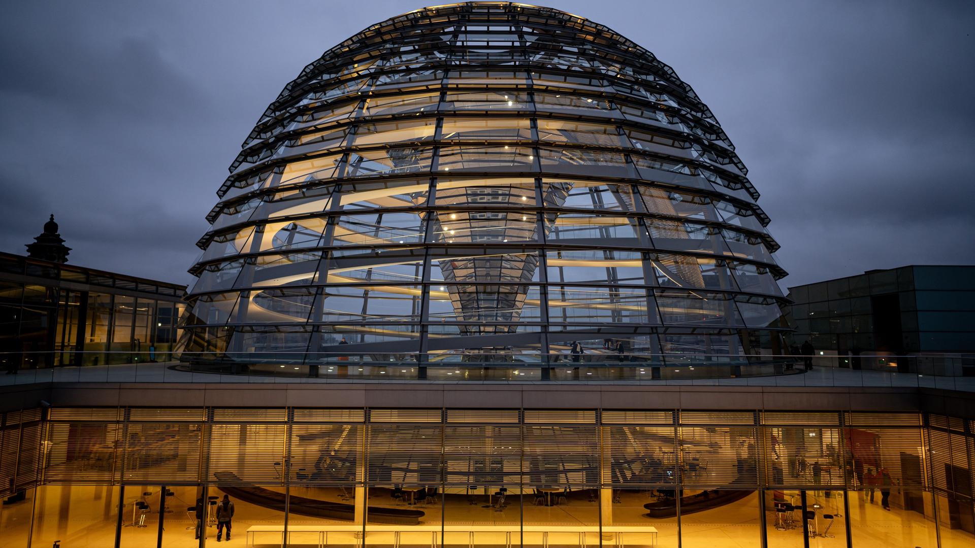 Die Kuppel des Reichstagsgebäudes wird am Morgen erleuchtet. 