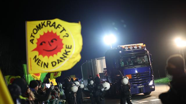 Ein großer Lastwagen mit einem Castor-Behälter fährt an Teilnehmer einer Anti-Atomkraft-Demonstration vorbei.