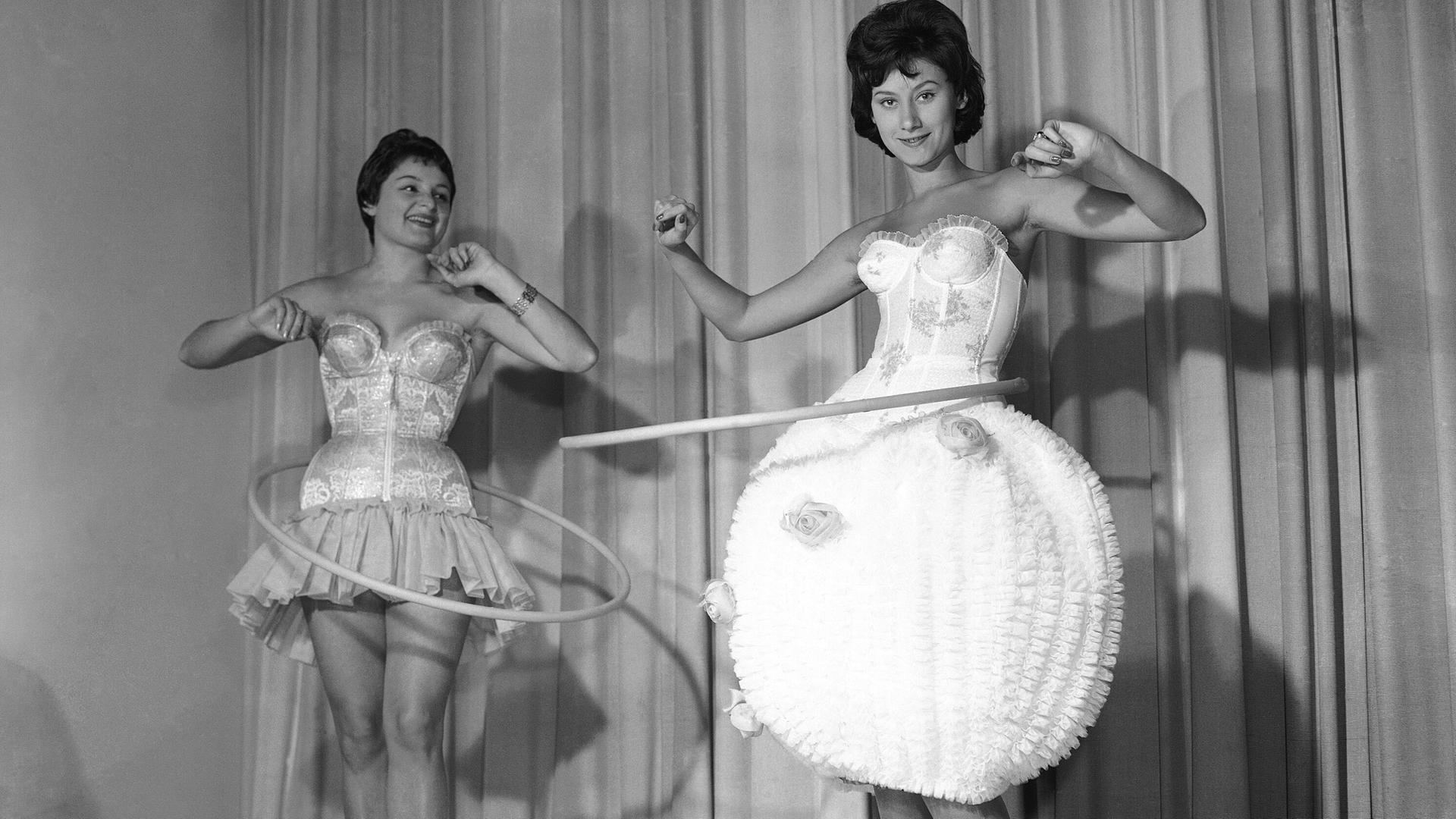 Schwarzweiß-Aufnahme von zwei jungen Frauen auf einer Bühne mit Hula-Hoop-Ringen um die Hüften