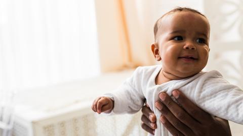 Eine Person hält ein Baby hoch.