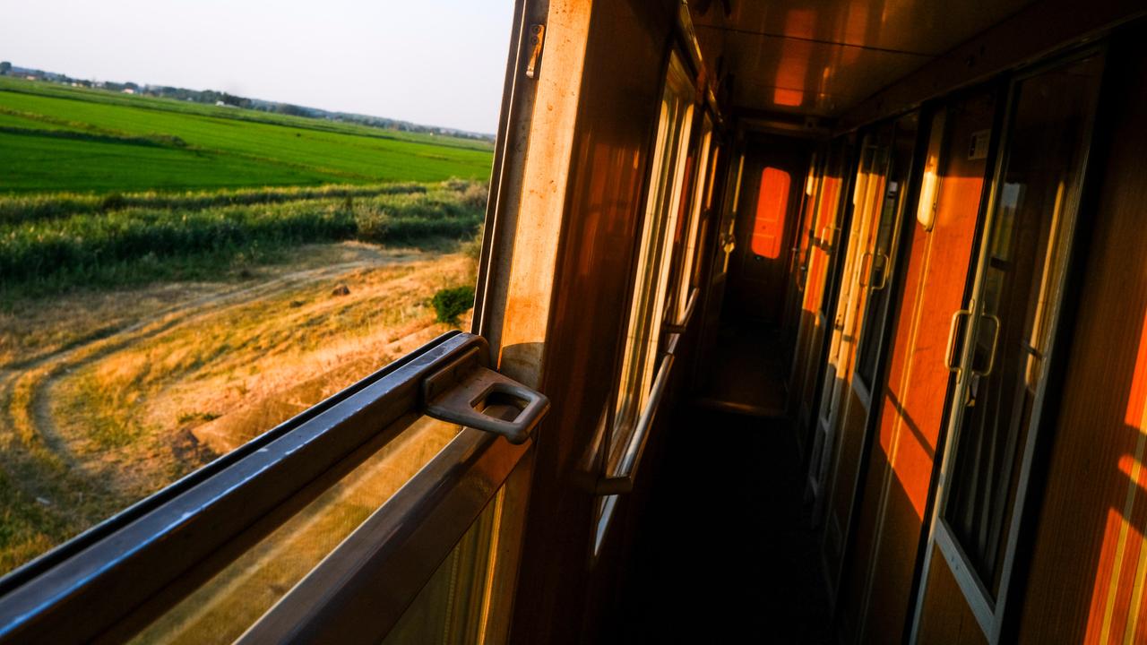 Ein Zug von innen im warmen Abendlicht mit Blick aus dem geöffneten Fenster in eine Feldlandschaft. 