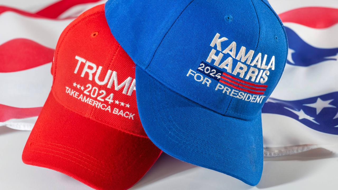 Rotes Basecap mit Trump-Logo und blaues mit Harris-Logo