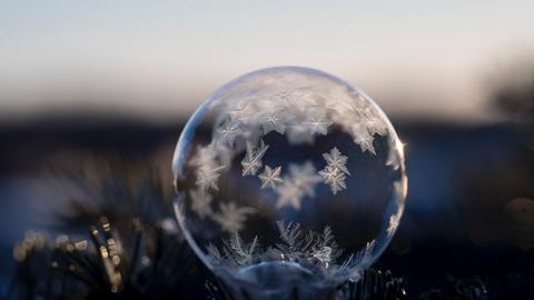 Auf einer Glaskugel sind Schneeflocken festgefrohren.