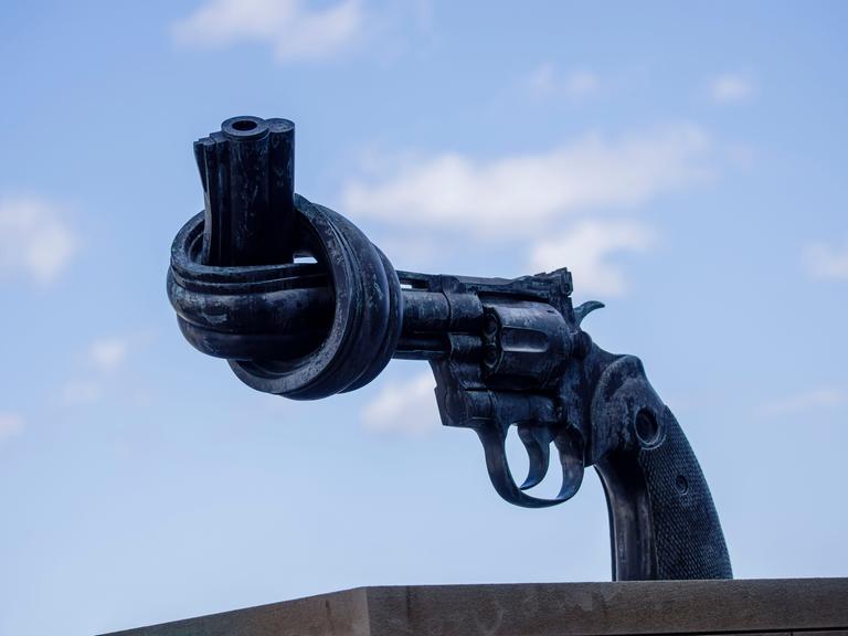 Eine Skulptur symbolisiert einen Revolver. Dessen Lauf sist zu einem Knoten verbogen. Die Skulptur steht vor dem Hauptgebäude der Vereinten Nationen in New York. Eine Skulptur symbolisiert einen Revolver. Dessen Lauf sist zu einem Knoten verbogen. Die Skulptur steht vor dem Hauptgebäude der Vereinten Nationen in New York.