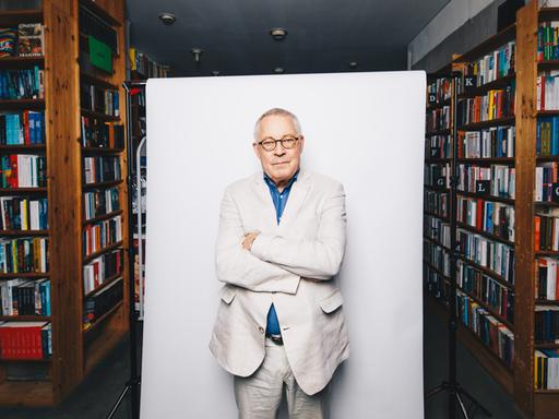 Der Autor Karl Schlögel posiert vor weißer Hintergrundaufhängung in der Buchhandlung am Bayrischen Platz in Berlin.