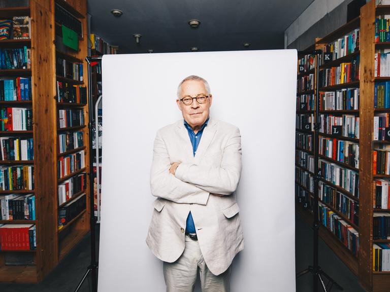 Der Autor Karl Schlögel posiert vor weißer Hintergrundaufhängung in der Buchhandlung am Bayrischen Platz in Berlin.