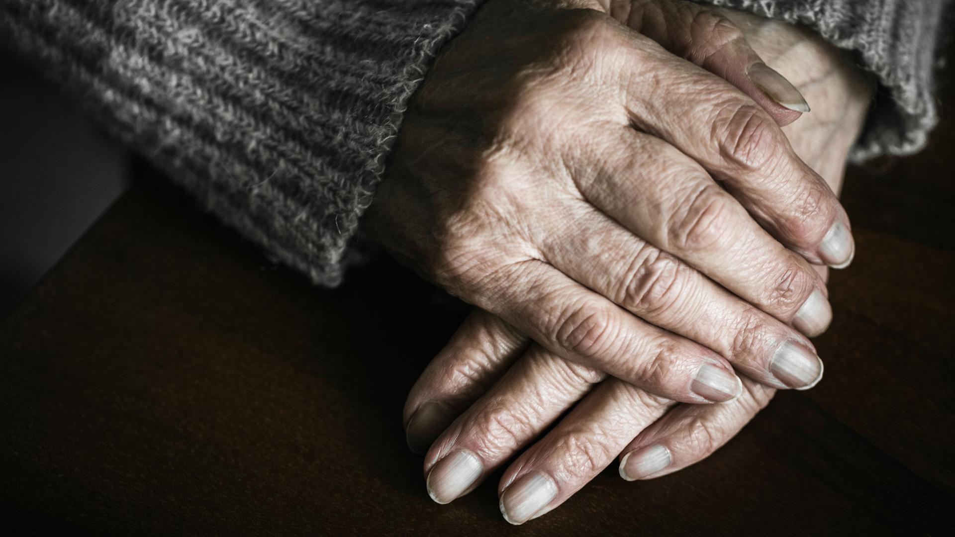Wer ist die namenlose, unheimliche Alte, die ungefragt in seine Wohnung eindringt Zu sehen: Die Hände einer alten Frau übereinander gelegt. 