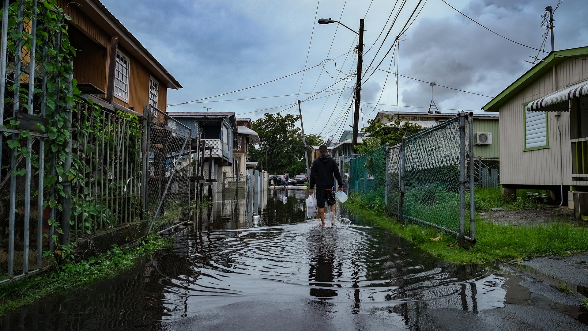 Ein Mann mit Einkaufstüten läuft durch eine überflutete Straße im Viertel Juana Matos in Catano, Puerto Rico. Ein Mann mit Einkaufstüten läuft durch eine überflutete Straße im Viertel Juana Matos in Catano, Puerto Rico.