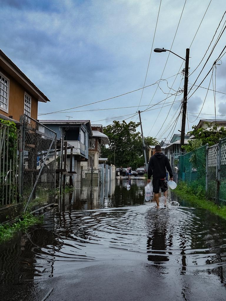 Ein Mann mit Einkaufstüten läuft durch eine überflutete Straße im Viertel Juana Matos in Catano, Puerto Rico.