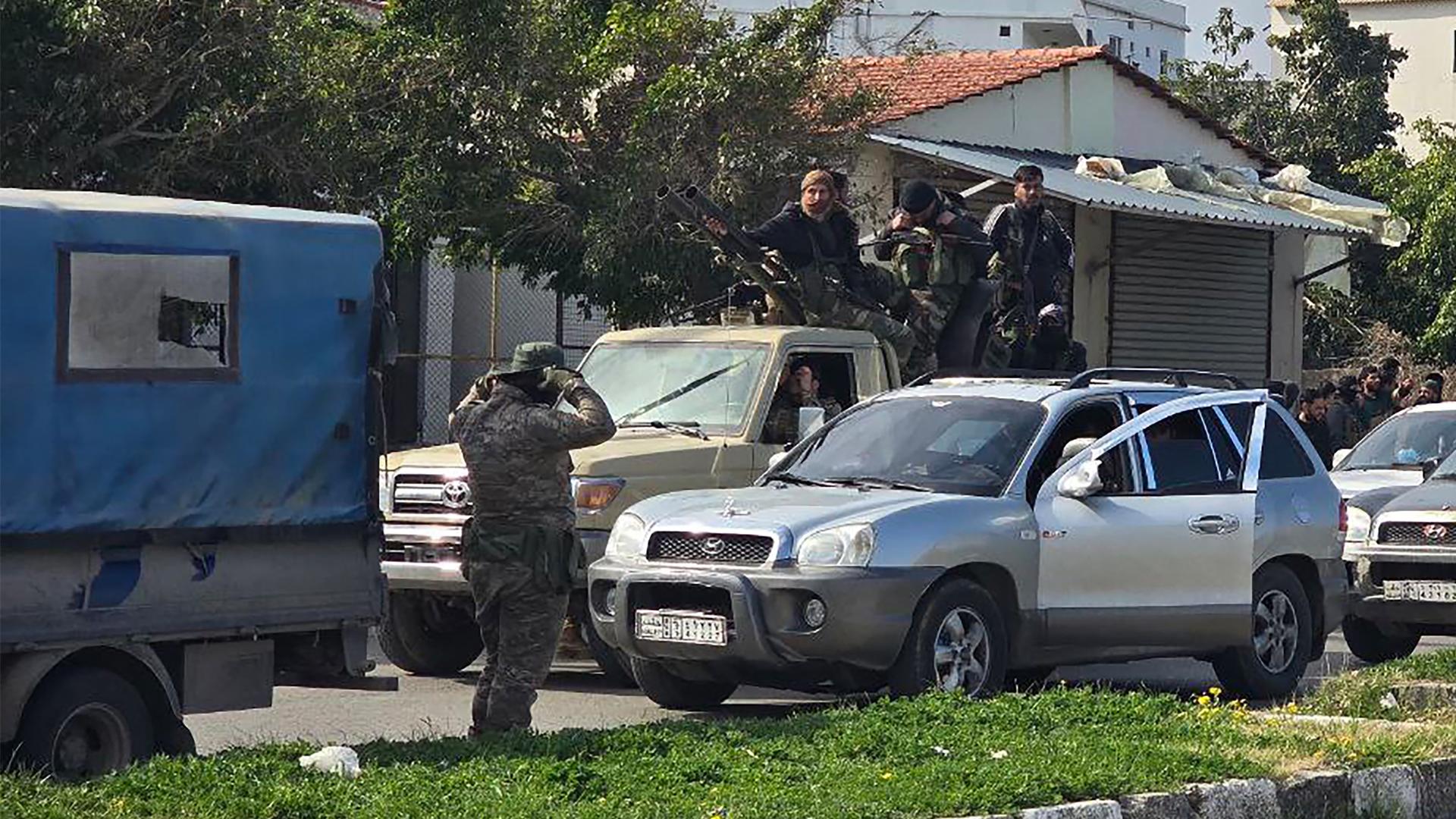 Männer aus den Truppen der syrischen Übergangsregierung sitzen bewaffnet auf einem Auto.