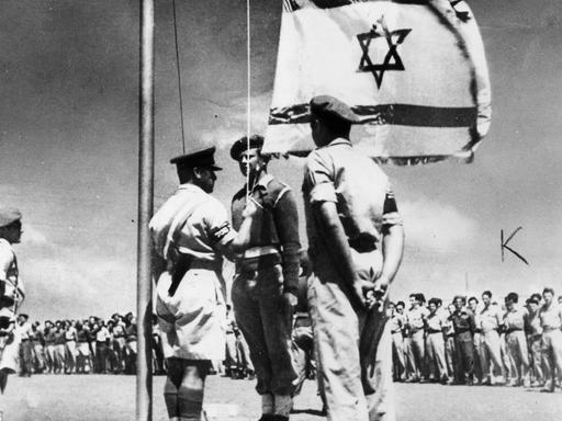 Historische Schwarz-weiß-Aufnahme zeigt das zeremonielle Aufziehen der israelische Flagge am 14. Mai 1948 zur Gründung des Staates Israel.