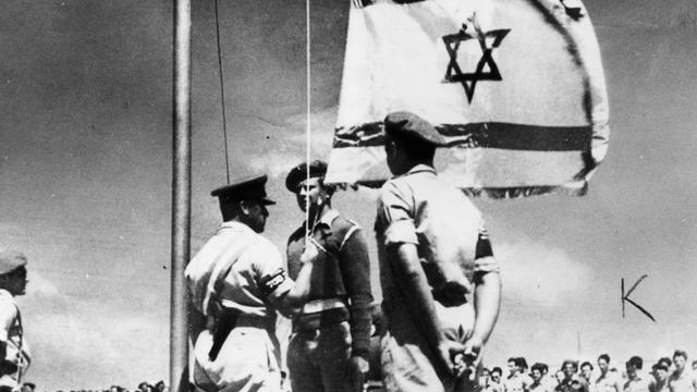 Historische Schwarz-weiß-Aufnahme zeigt das zeremonielle Aufziehen der israelische Flagge am 14. Mai 1948 zur Gründung des Staates Israel.