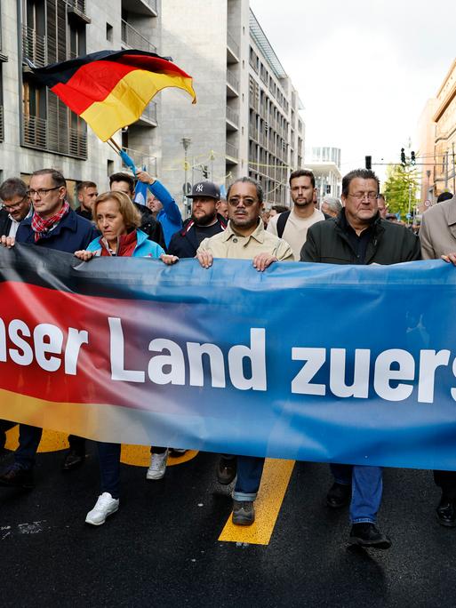 Führende AfD-Politiker während einer Demonstration in Berlin. Sie halten ein Banner mit der Aufschrift "Unser Land zuerst".