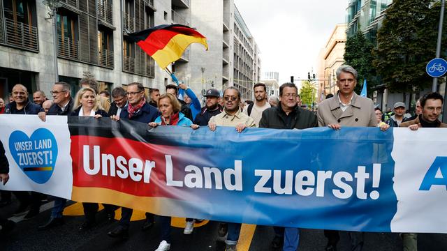 Führende AfD-Politiker während einer Demonstration in Berlin. Sie halten ein Banner mit der Aufschrift "Unser Land zuerst".