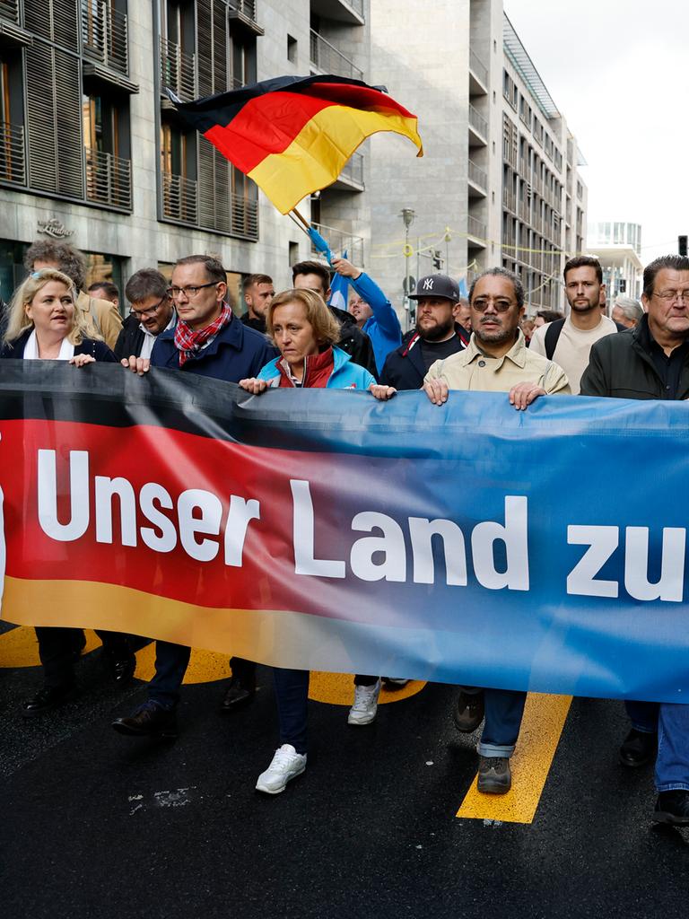 Führende AfD-Politiker während einer Demonstration in Berlin. Sie halten ein Banner mit der Aufschrift "Unser Land zuerst".