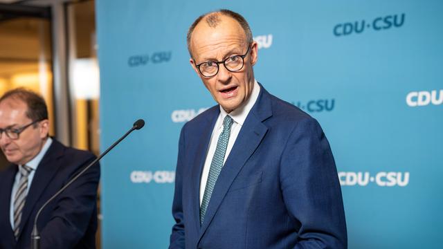 Union-Kanzlerkandidat Friedrich Merz am Mikrofon vor blauer Wand mit CDU-CSU-Aufschrift.