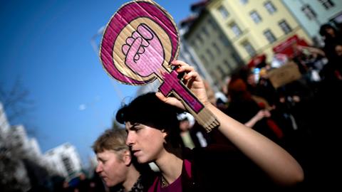 Demonstrantin hält ein Schild mit aufgemaltem Symbol für Frauenpower 