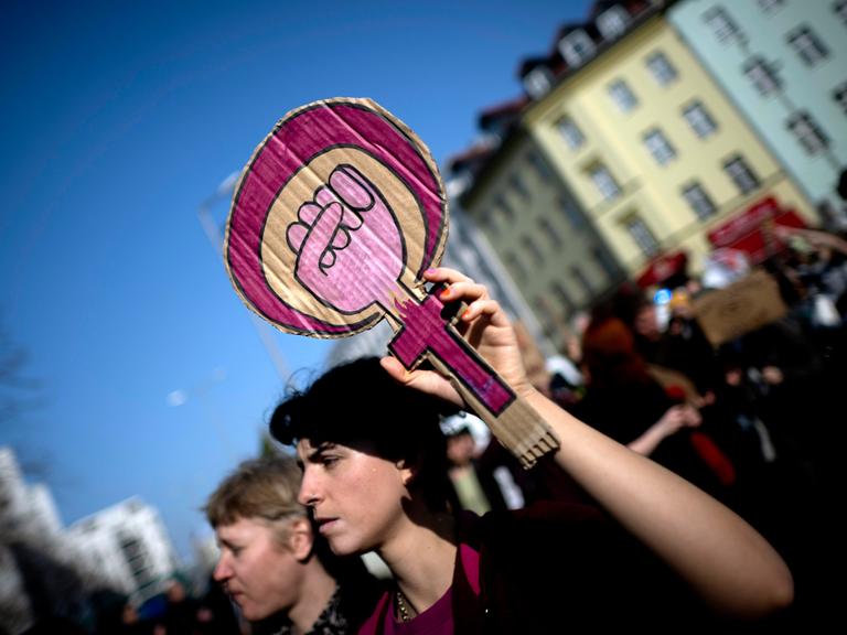 Demonstrantin hält ein Schild mit aufgemaltem Symbol für Frauenpower 