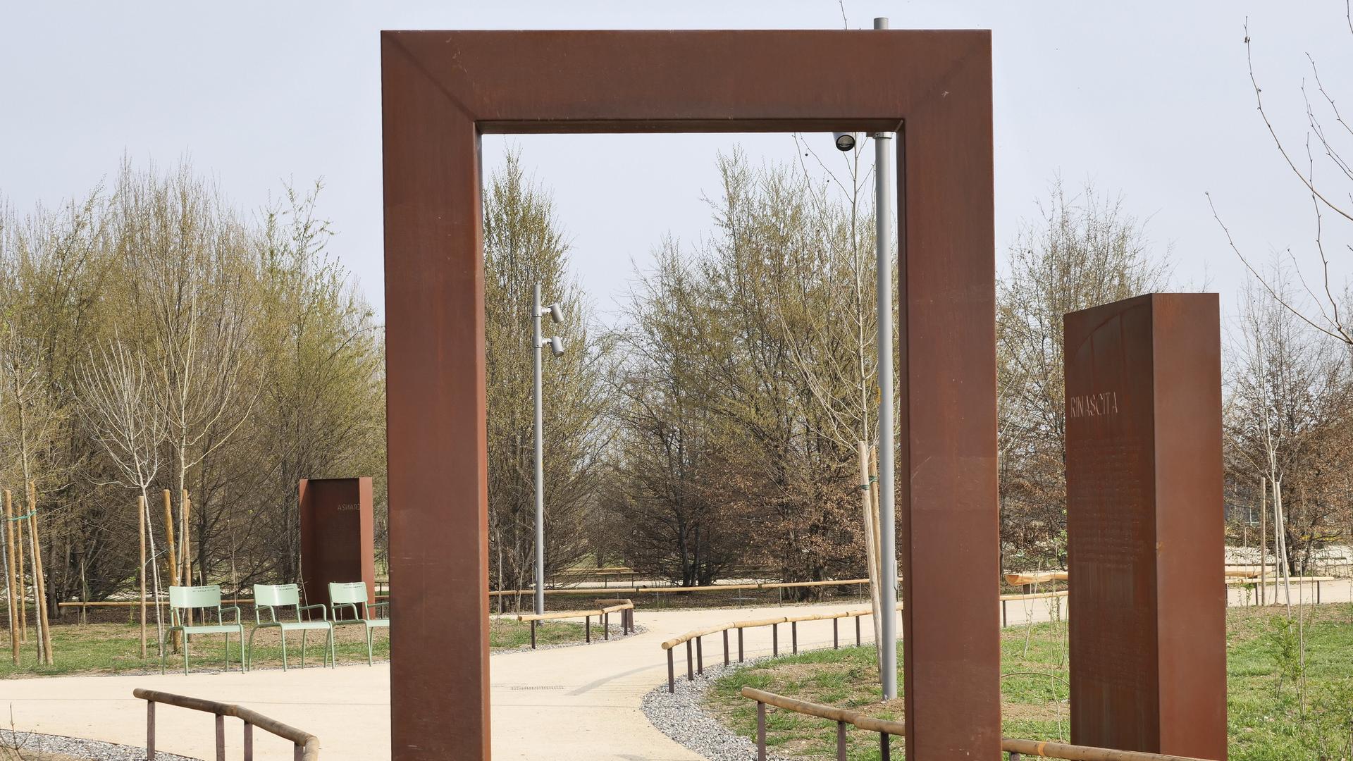 Blick durch ein großes Stahltor auf eine parkähnliche Anlage