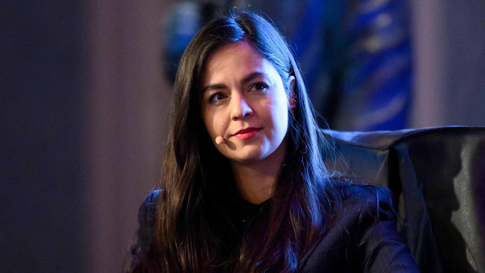 Shahrzad Osterer, mit einem Ansteckmikrofon, im dunklen Sakko, nimmt an einer Podiumsdiskussion teil.