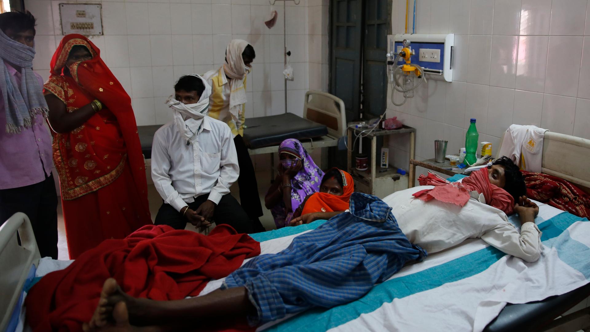 Familienangehörige stehen in einem Krankenhaus in Varanasi in Indien am Bett eines Patienten, der an Tuberkulose leidet. 