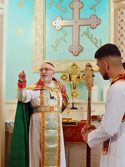 Ein Pfarrer steht vor dem Altar, um ihn herum vier Ministranten.