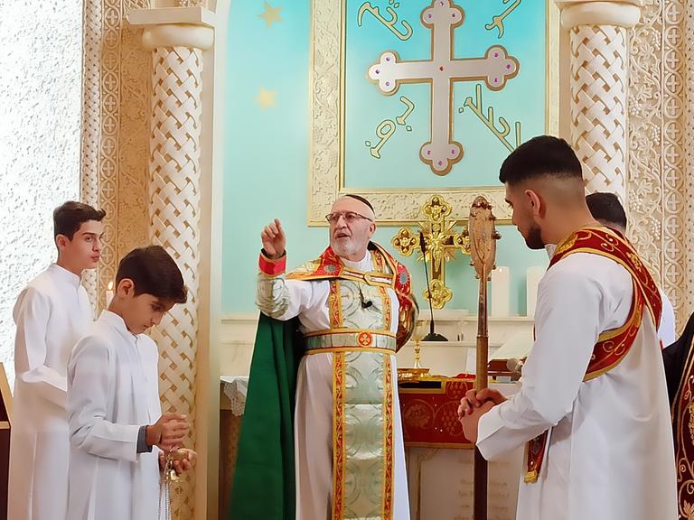 Ein Pfarrer steht vor dem Altar, um ihn herum vier Ministranten.